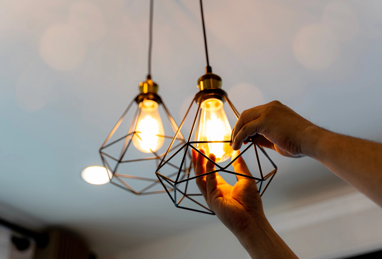 Person installing geometric pendant light fixture