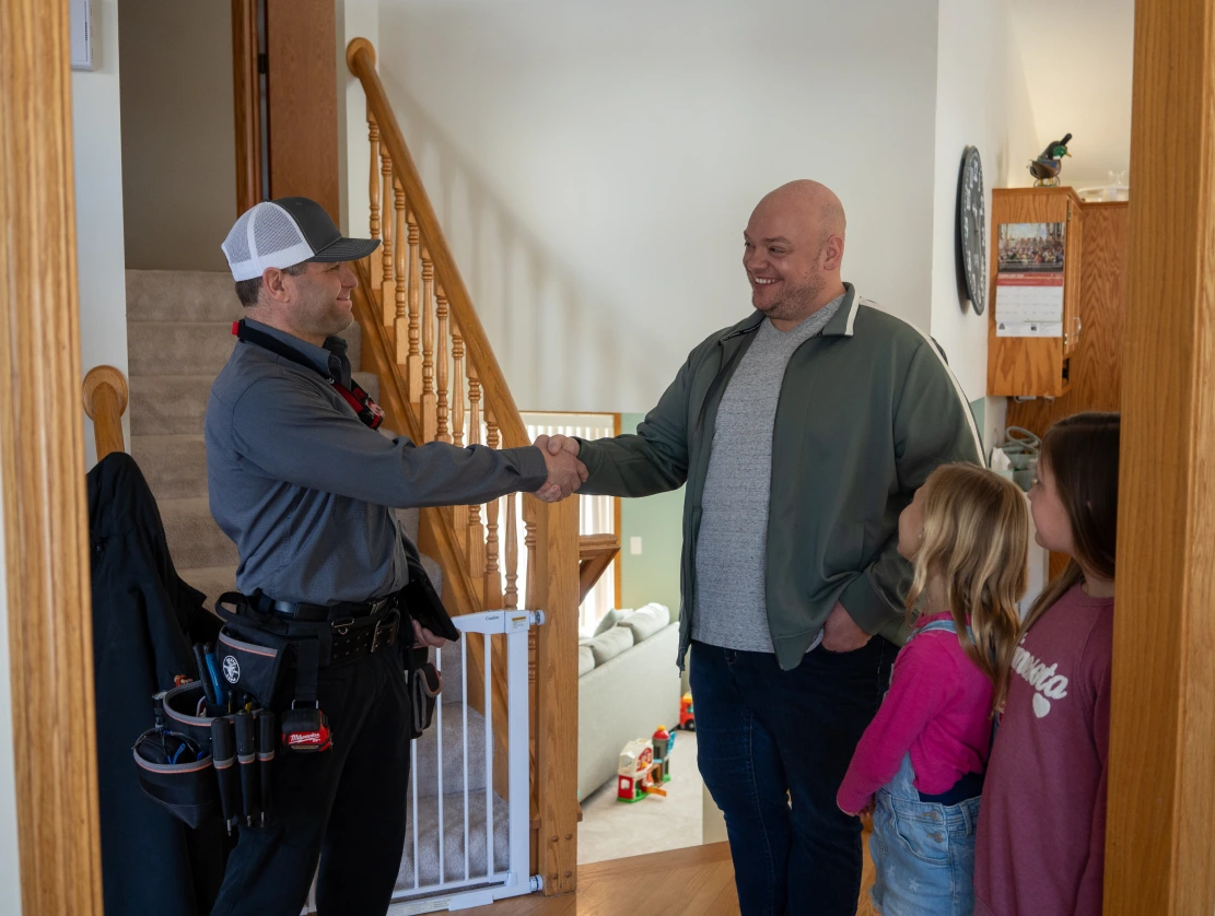 Electrician shaking hands with homeowner family after approving electrical service financing in Rochester, MN